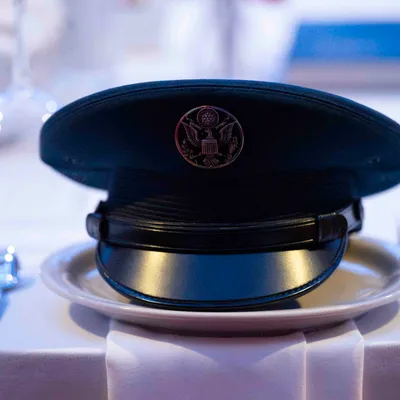 A service cap resting on a plate at a formal place setting