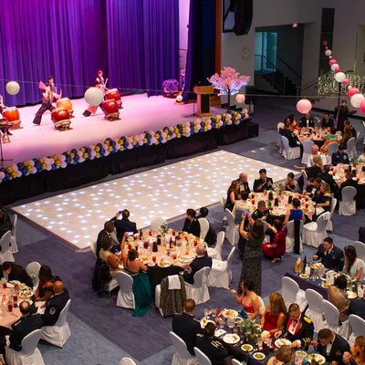 A banquet hall with a stage, dance floor, and guests at round tables